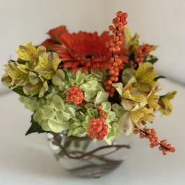 Mixed bouquet with orange gerbera, yellow alstroemeria, and green hydrangea in a glass vase