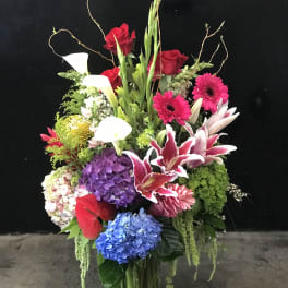 Tall mixed bouquet with roses, lilies, calla lilies, and hydrangeas in a glass vase
