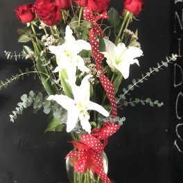 Red roses and white lilies in a glass vase with a red polka-dot ribbon