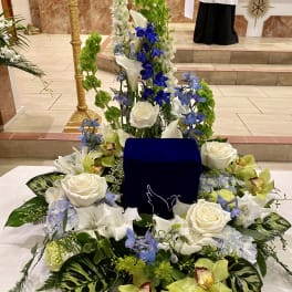 Large white and blue floral arrangement around a dark blue urn