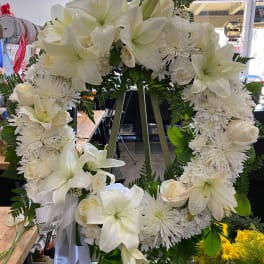 White floral wreath with lilies, roses, and chrysanthemums on an easel