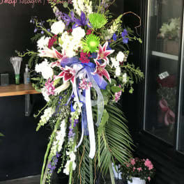 Tall standing floral spray with lilies, snapdragons, and ribbon