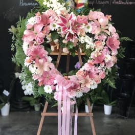 Heart-shaped pink floral wreath on an easel with a ribbon bow