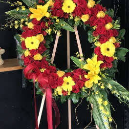 Heart-shaped floral wreath of red and yellow roses with ribbon on an easel