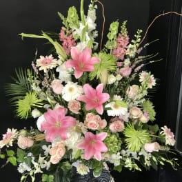 Large floral spray with pink lilies, roses, and white daisies on a pedestal