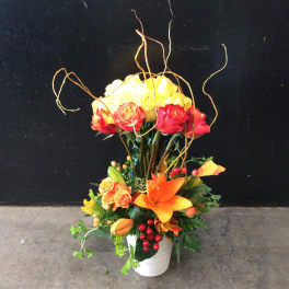 Tall floral arrangement with yellow and red roses in a white vase
