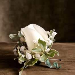 White rose boutonniere with small white filler flowers and variegated greenery