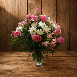 Pink roses and white daisies arranged in a clear glass vase