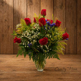 Red roses arranged in a clear glass vase with white filler flowers