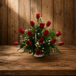 Red roses arranged in a white basket with small white filler flowers