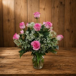 Pink roses arranged in a clear glass vase with white filler flowers