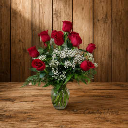 Red roses arranged in a clear glass vase with white filler flowers