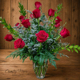 Red roses arranged in a clear glass vase with white filler flowers