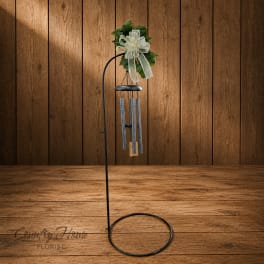 Wind chime with a white ribbon bow and greenery topper