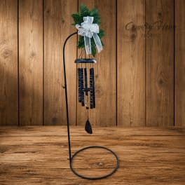 Black metal wind chime with green foliage and a white bow