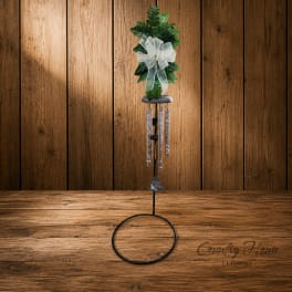 Green memorial wind chime with a white bow on a metal stand