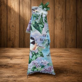 Decorative memorial blanket on a stand with a white bow and greenery