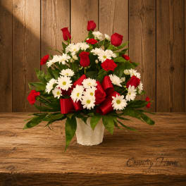Red roses and white daisies in a white vase with red ribbon