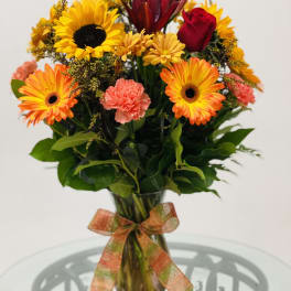 Bright mixed bouquet in a glass vase with a ribbon