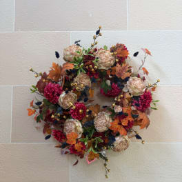 Autumn wreath with pink flowers and beige blooms on a wall