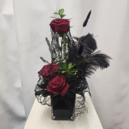 Red roses in a black vase with black feathers and netting