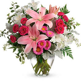 Pink lilies and roses in a clear glass vase with white flowers