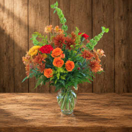 Mixed orange and red flowers arranged in a clear glass vase