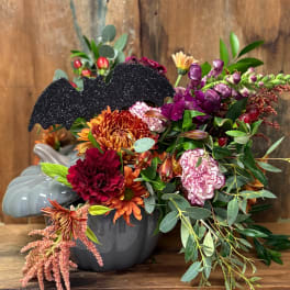 Halloween floral arrangement in a gray pumpkin vase with a glitter bat pick
