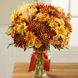 Bouquet of yellow and red flowers in a glass vase with a red ribbon
