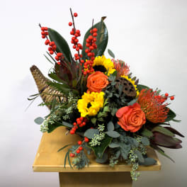 Mixed floral arrangement with sunflowers, orange roses, and red berry stems