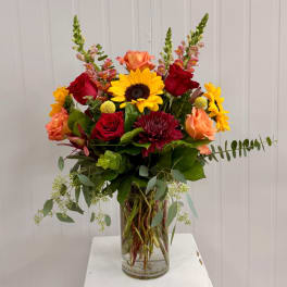 Mixed bouquet in a clear glass vase with sunflowers and red roses
