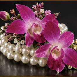Pink orchids arranged with pearl beads on a black surface