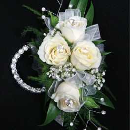 White rose corsage with silver ribbon and rhinestone accents on a black background