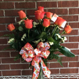 Orange rose bouquet in a glass vase with a patterned ribbon