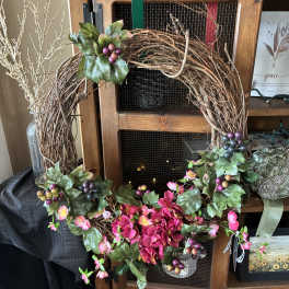 Decorative grapevine wreath with pink flowers and berry clusters