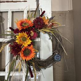 Fall wreath with sunflowers and burgundy flowers on a grapevine ring