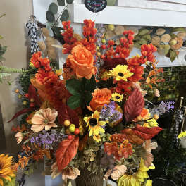 Autumn floral arrangement with orange, yellow, and peach blooms in a brown vase
