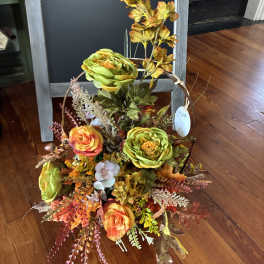Autumn floral basket with orange and green blooms and fall foliage