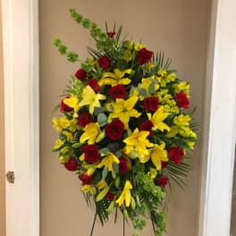 Standing floral spray with red roses and yellow lilies on a metal easel