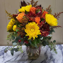 Mixed bouquet of yellow chrysanthemums and orange roses in a glass vase