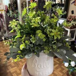 Green floral arrangement in a white ceramic pot