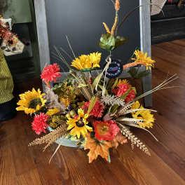 Autumn floral arrangement with sunflowers and red blooms in a low container