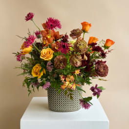 Mixed bouquet in a patterned metal vase with orange and purple blooms