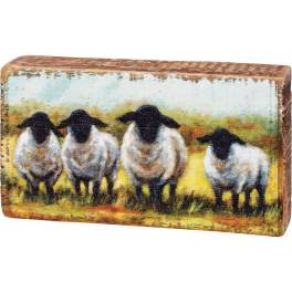 Rectangular decorative block with painted sheep on a rustic wood surface