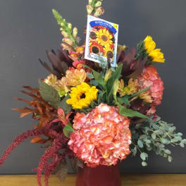 Mixed bouquet with sunflowers and pink hydrangea in a red vase