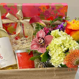 Gift basket with flowers, wine bottle, candle, and ribboned box