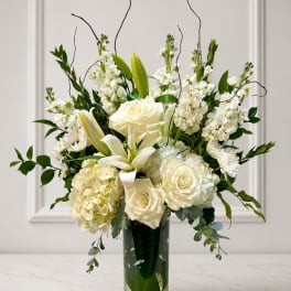 White roses and lilies arranged in a tall glass vase