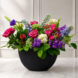 Colorful mixed flower arrangement in a black bowl vase