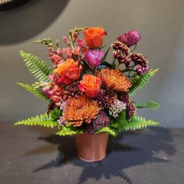 Orange and purple mixed flower arrangement in a copper pot