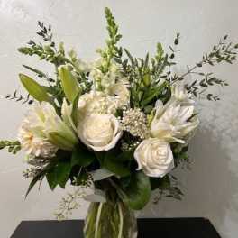 White roses and lilies arranged in a clear glass vase